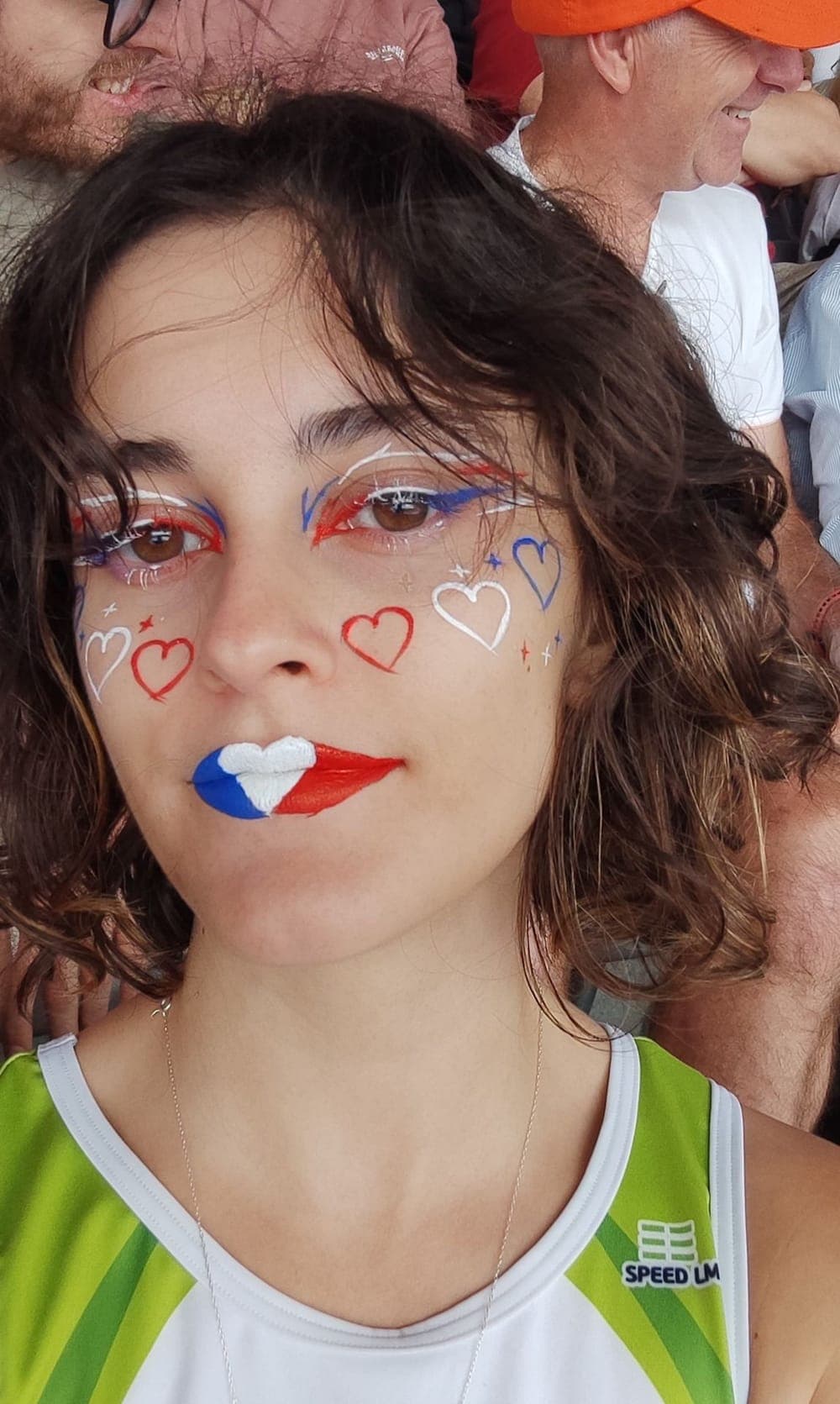 Close-up of a face made up in blue, white and red in the stands of a stadium
